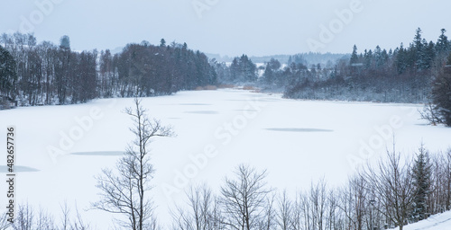 Winter frozen pond covered in snow dark sky
