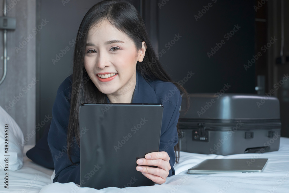 Young businesswoman using tablet working in hotel room during her business travel. Businesswoman working from hotel room on business trip. Female in a hotel room. Young businesswoman using tablet working in hotel room during her business travel. Businesswoman working from hotel room on business trip. Female in a hotel room.