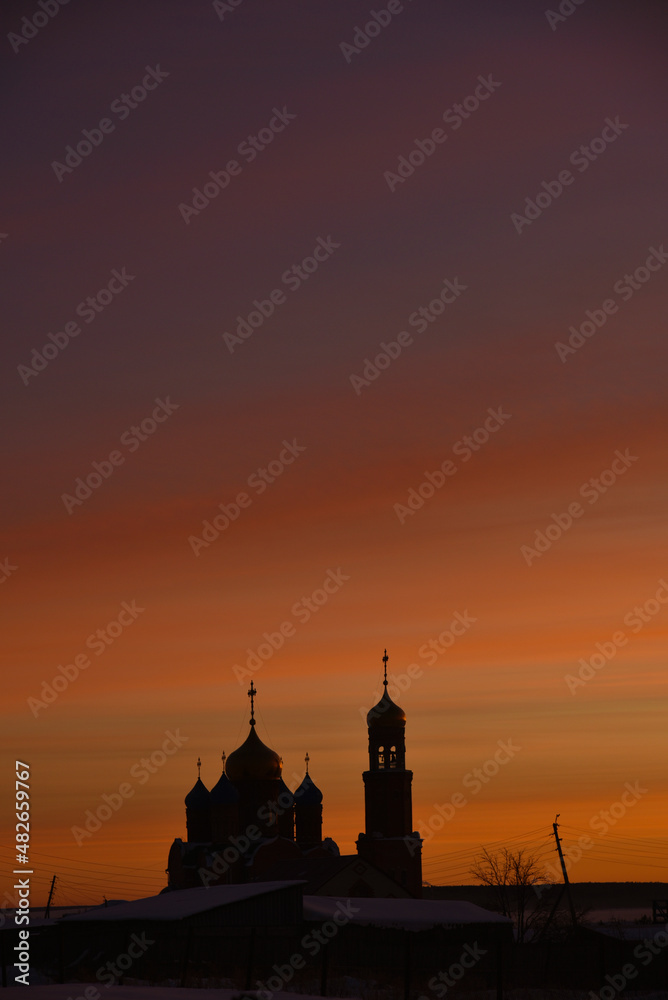Christian church on the background of a red sunset