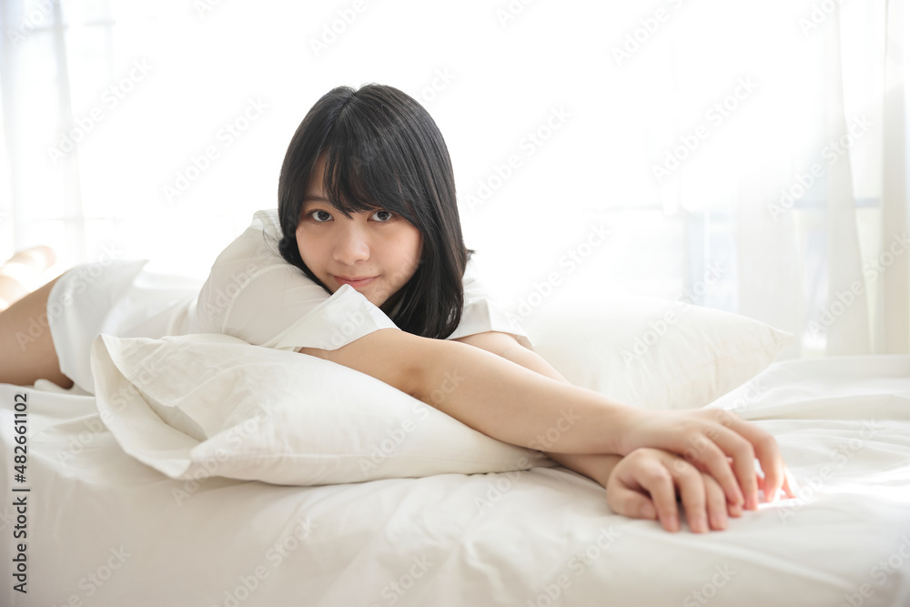 Beautiful young woman waking up in the morning at white bedroom Beautiful young woman waking up in the morning at white bedroom