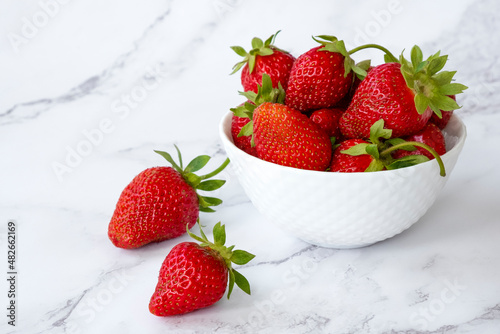 Delicious juicy strawberries in white bowl on marble background. Healthy eating  raw diet and detox food concept. Farm strawberry harvest.