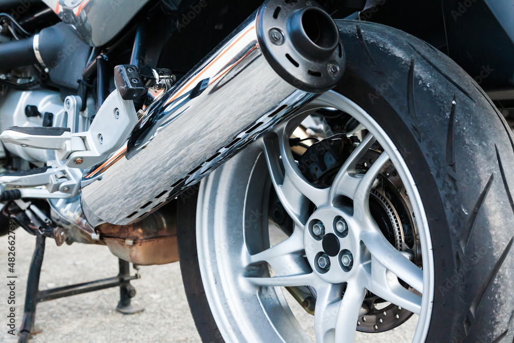 The rear wheel of a powerful sports bike with chrome tailpipe. The rear wheel of a powerful sports bike with chrome tailpipe.