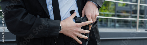 Φωτογραφία partial view of security man taking gun out of holster outdoors, banner
