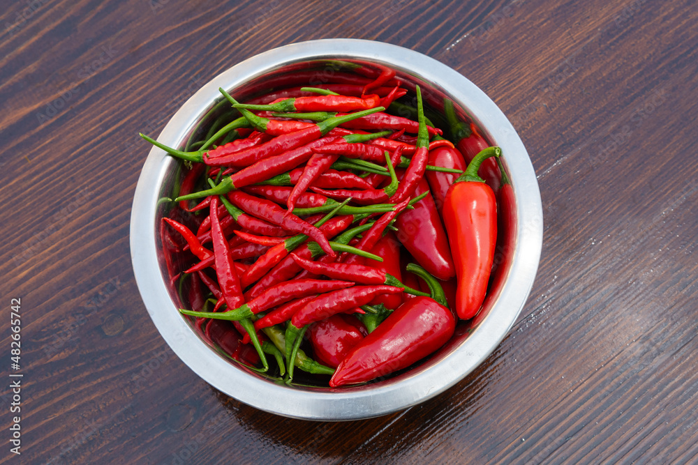Mixed red hot chili peppers in bowl on a wooden table Mixed red hot chili peppers in bowl on a wooden table