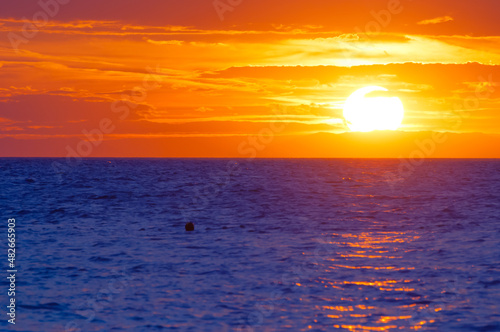 Radiant orange sunset over blue wavy sea