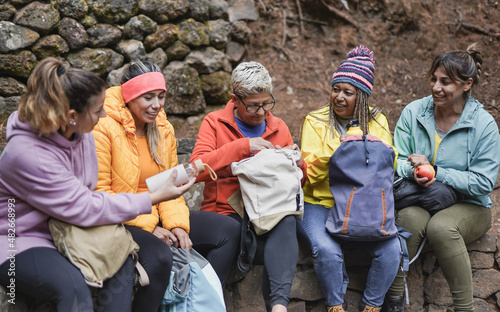 Multiracial women having a break during trekking day in the forest - Multi generational female friends enjoy day in nature