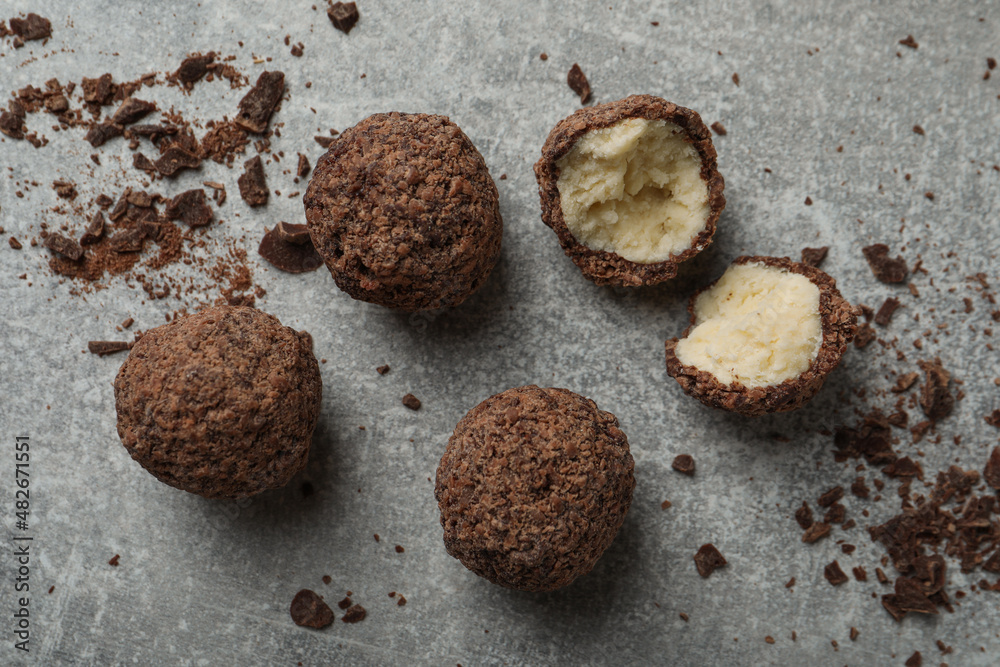 Many delicious chocolate truffles on grey table, flat lay