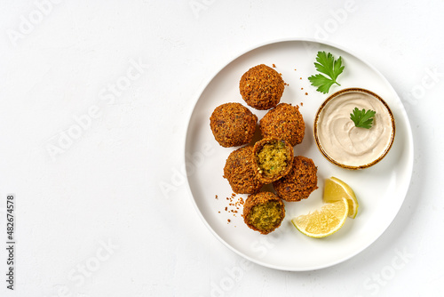 Plate of chickpeas falafel with tahini sauce isolated on white background. Top view, copy space photo
