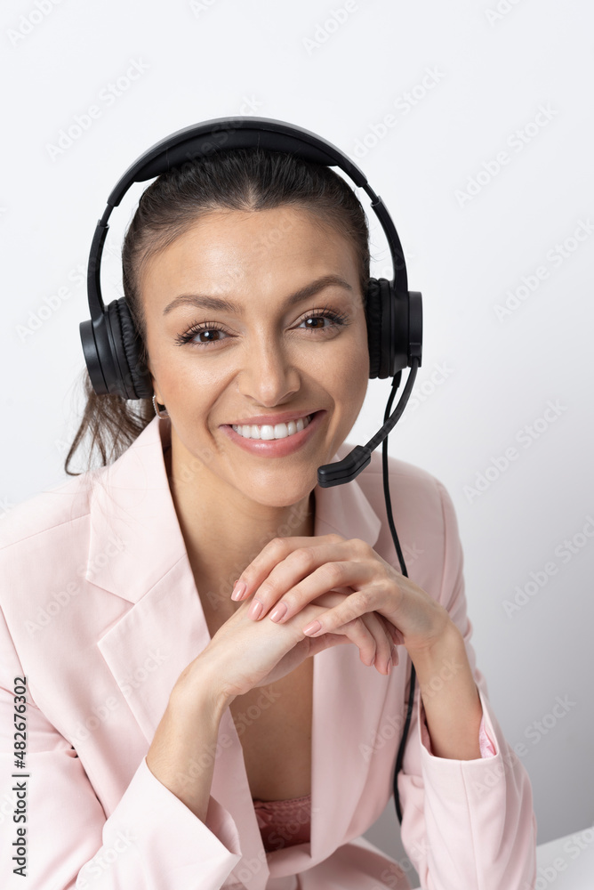 England, UK. 2021. Attractive woman wearing a telephone headset and wearing a pink jacket. England, UK. 2021. Attractive woman wearing a telephone headset and wearing a pink jacket.