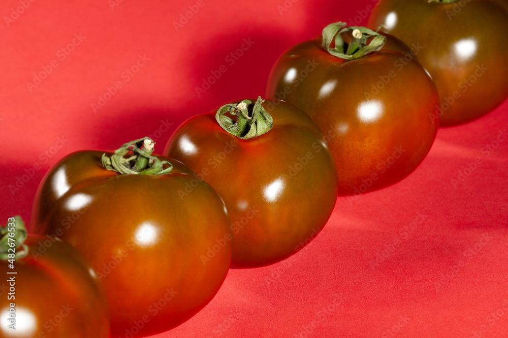 kumato tomato on red background kumato tomato on red background