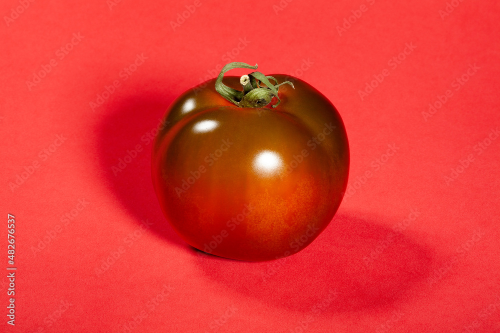 kumato tomato on red background kumato tomato on red background