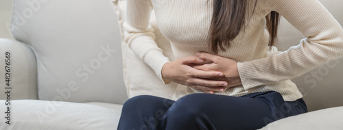 Flatulence asian young woman, girl hand in stomach ache, suffer from food poisoning, abdominal pain and colon problem, gastritis or diarrhoea. Patient belly, abdomen or inflammation, concept. photo