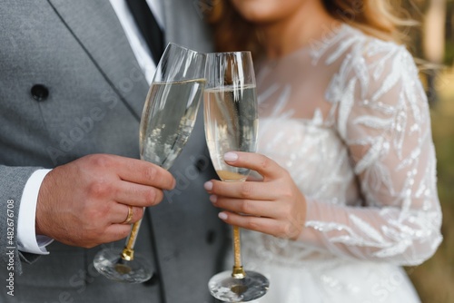 Hands of bride and groom holding champagne glasses with sparkling wine. Wedding celebration concept