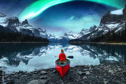 Traveler woman sitting on canoe with aurora borealis over Spirit Island in Maligne lake at Jasper national park photo