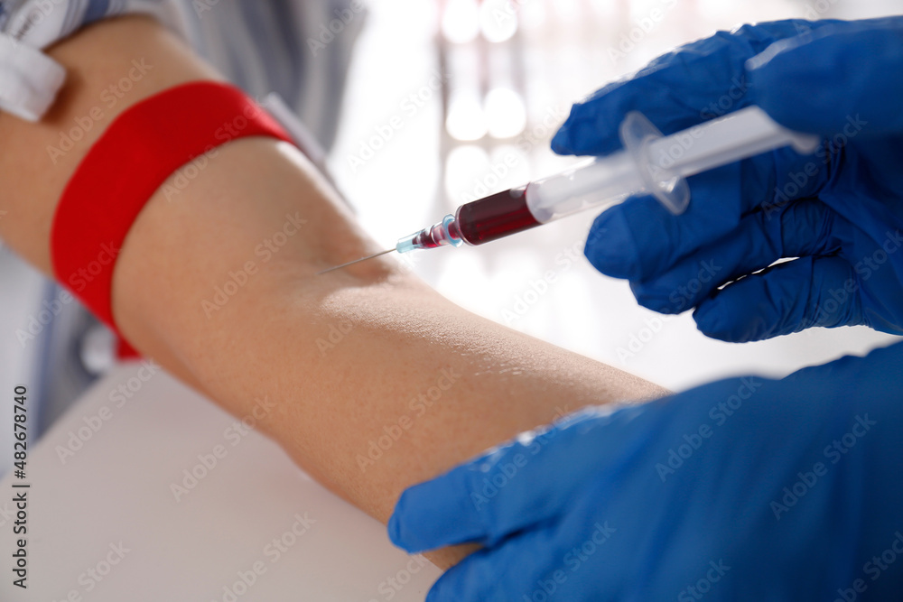 Nurse drawing blood sample from patient in clinic, closeup Nurse drawing blood sample from patient in clinic, closeup