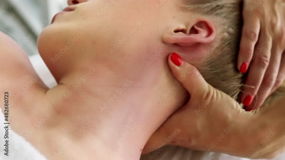 Relaxed woman receiving neck cervical spine massage in aesthetic salon. Getting procedure in beauty clinic. Stress relief and rejuvenation concept. Relaxed woman receiving neck cervical spine massage in aesthetic salon. Getting procedure in beauty clinic. Stress relief and rejuvenation concept.