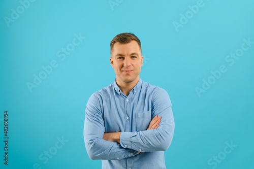 Happy smiling handsome man in clothing, showing copy space, visual imaginary or something, or pressing virtual button, aqua marine blue color background.