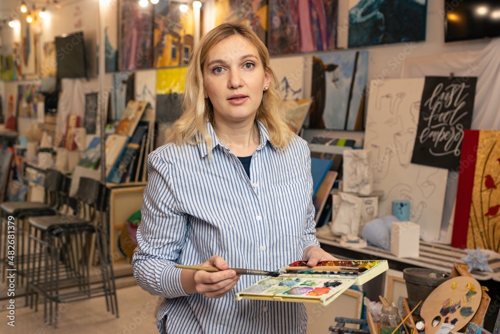 Portrait of a young woman with watercolor paints in an art studio