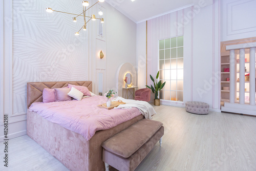 luxurious modern bedroom interior of an expensive spacious light stylish apartment. upholstered furniture and decorative lighting  soft pastel colors and cozy atmosphere