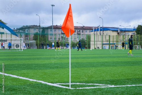 Corner flag in red on green soccer field