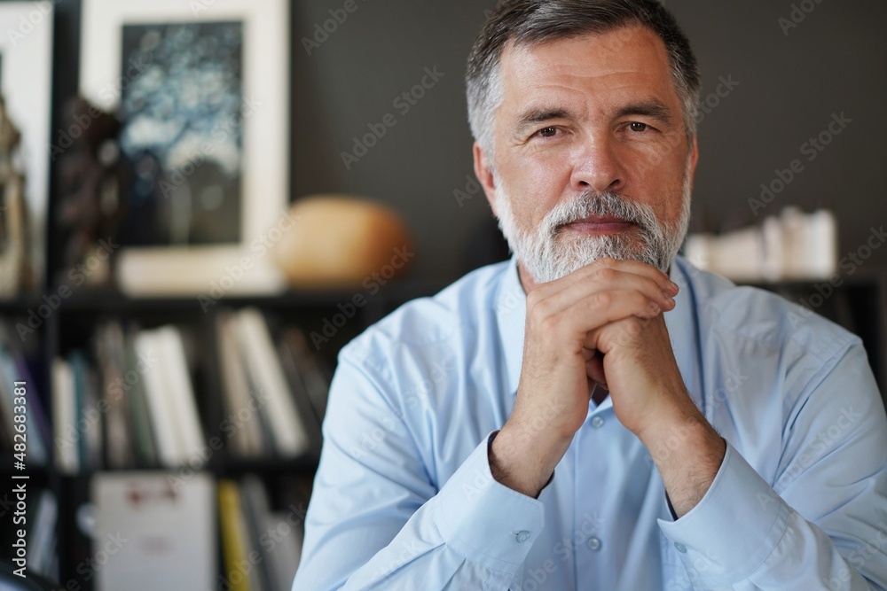 Mature professional businessman looking at camera and smiling. Confident entrepreneur, leader, manager sitting in office - obrazy, fototapety, plakaty 