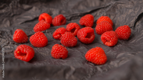 Raspberry fresh fruits photographed on a dark background. Raspberries food photography. Details of this tasty forest fruits.