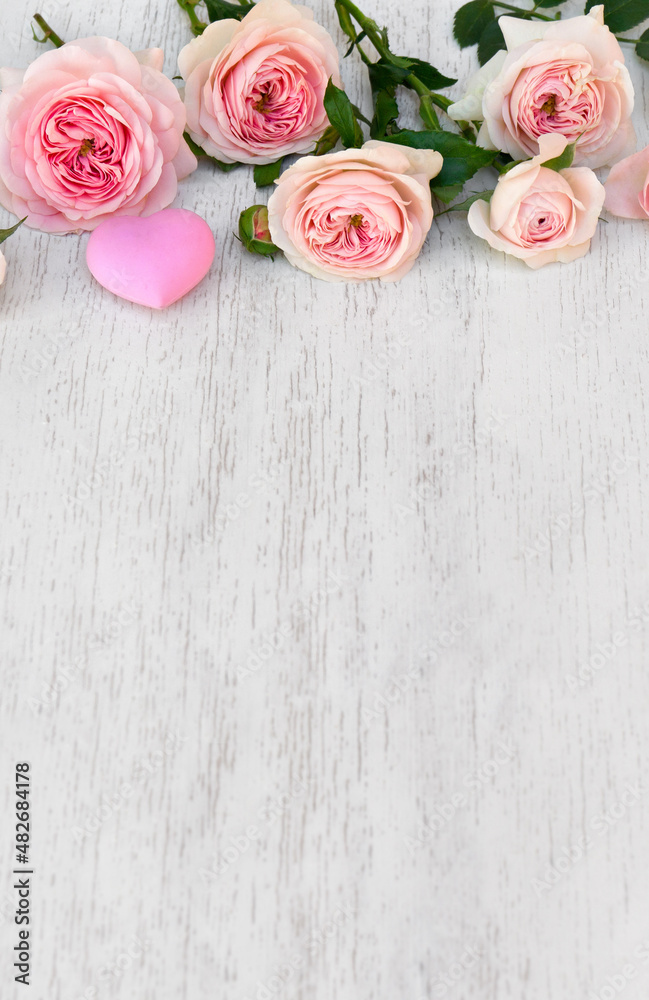 Flowers pink roses with hearts on a white wooden background with space for text. Decoration of Valentine Day