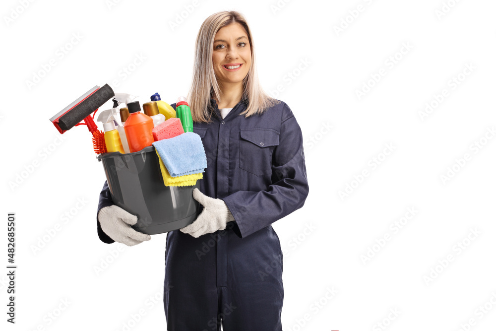 Young female cleaner in a uniform holding a bucket of cleaning supplies and smiling Young female cleaner in a uniform holding a bucket of cleaning supplies and smiling