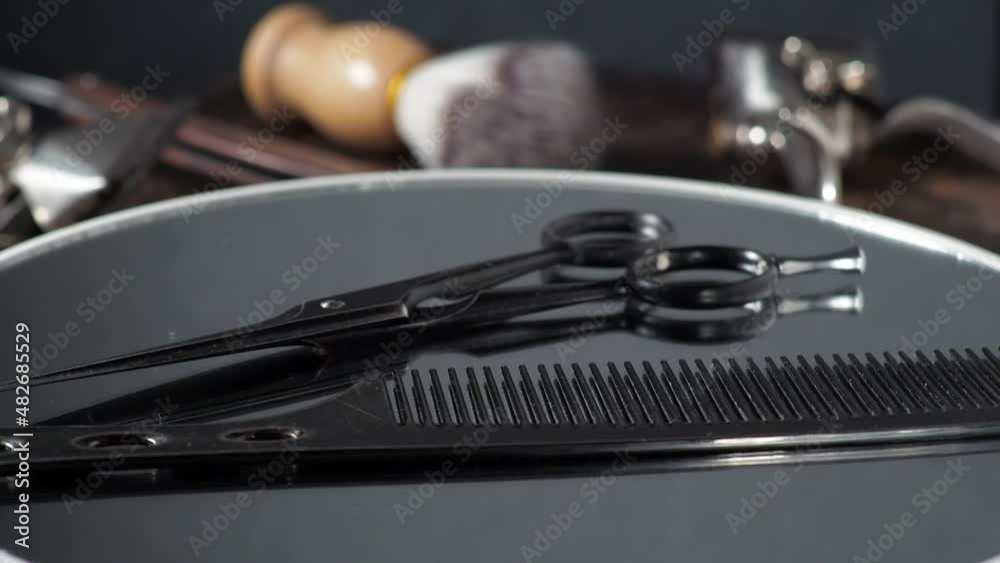 Hairdressing scissors and comb rotate on the mirror. Barber tools in the background. 4k Hairdressing scissors and comb rotate on the mirror. Barber tools in the background. 4k