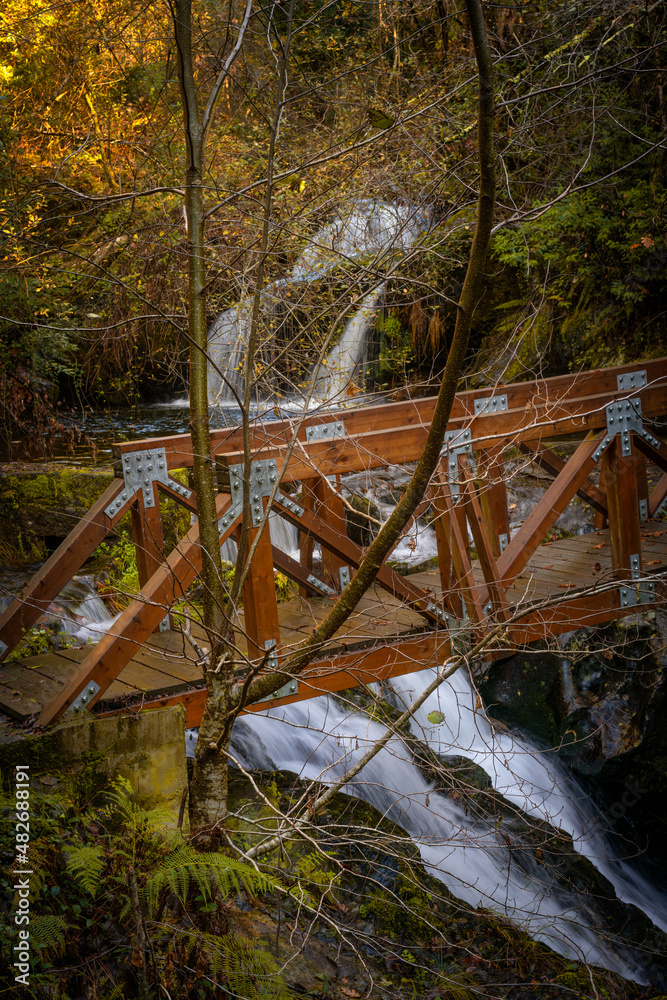 Wood bridge crossing a waterfall in the wild nature of Mondim de Basto