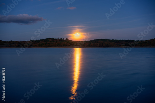 Full moon reflection on a lake at night in Sabugal Dam, Portugal