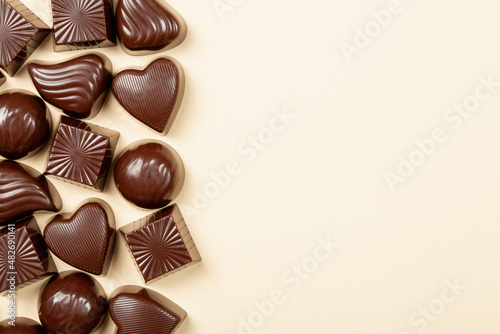 Chocolate pralines assortment on beige background, flat lay, top view with copy space