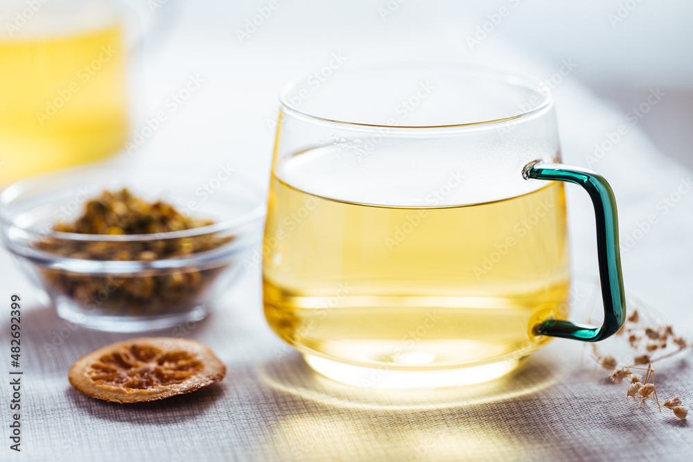 Cup of chamomile tea in transparent mug served with slice of lemon and orange. Tea break. 