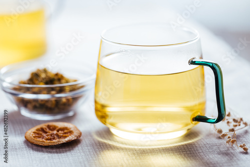 Cup of chamomile tea in transparent mug served with slice of lemon and orange. Tea break. 