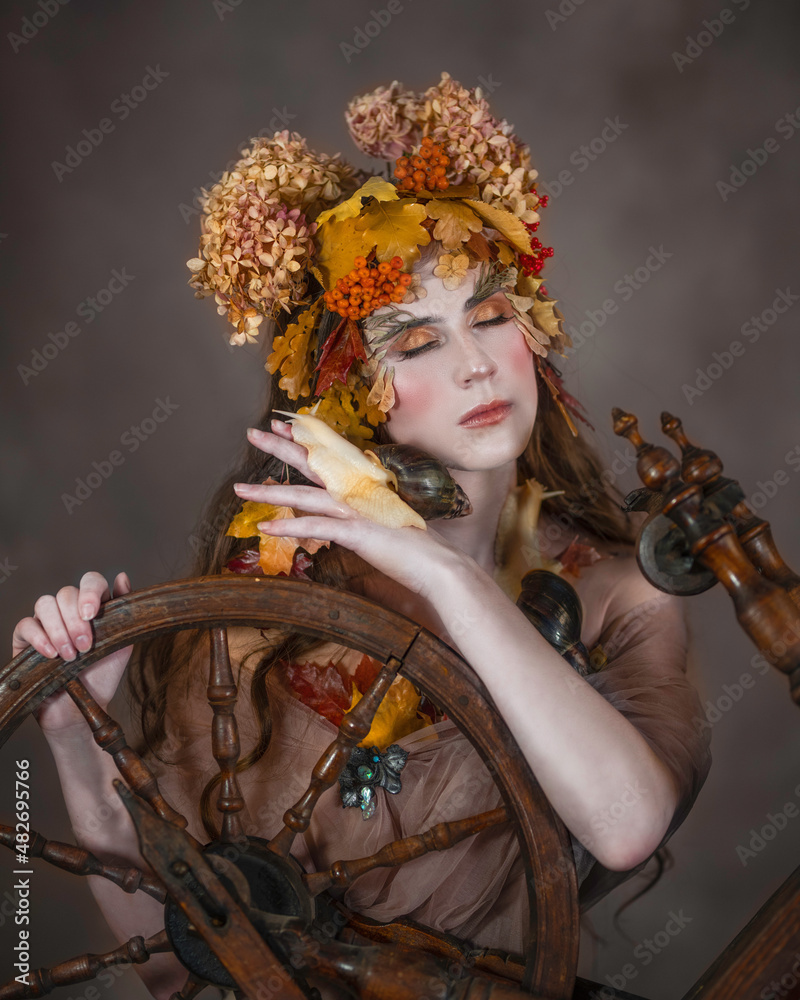Portrait of a girl in autumn leaves over a vintage spinning wheel Portrait of a girl in autumn leaves over a vintage spinning wheel