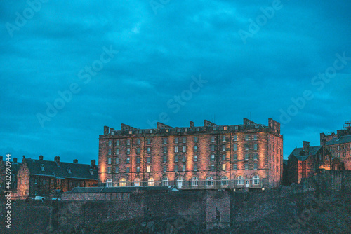 Stunning night aerial view of Edinburgh in Scotland, with the castle dominates the skyline, casting its shadow over the surrounding historic town occupying commanding position on cliffs photo