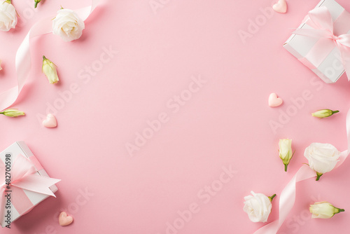 Top view photo of woman's day composition gift boxes with bows pink ribbon small hearts and prairie gentian flowers on isolated pastel pink background with copyspace
