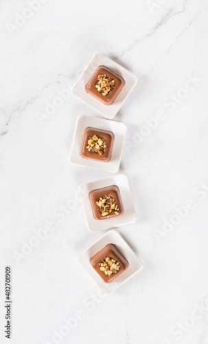 Vegan small Chocolate nut cream dessert in the shape of a square savarin on a plate on a white background. Top view