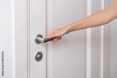 Hand opens the door metal handle. Woman hand using towel for cleaning home room door link. Sanitize surfaces prevention in hospital and public spaces against corona virus.