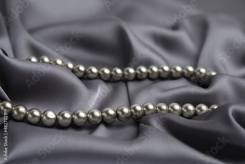 Beautiful silver pearls on grey silk, closeup