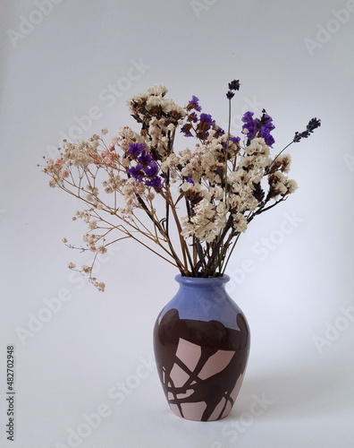 A bouquet of dried flowers in a ceramic vase. White and purple inflorescences of statice, limonium sinuatum, wavyleaf sea lavender. The work of a florist. photo