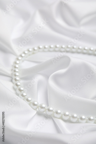 Beautiful pearls on white silk, closeup view