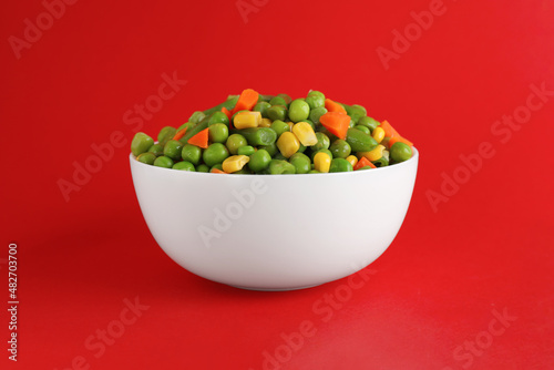 Mix of fresh vegetables in bowl on red background