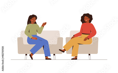 Two women sit on the couches and talk about something. Female host listening to her guest story-telling. Psychotherapist has a session with her patient. Business interview and Conversation concept.