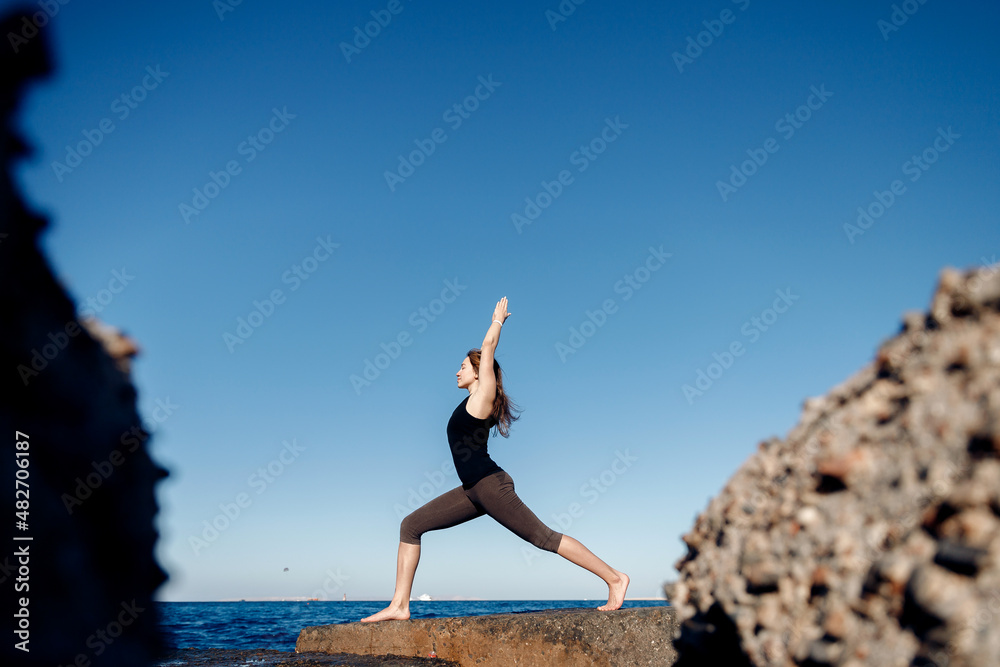 Young woman practicing yoga healthy life, meditation background sea blue water. Concept different asana on beautiful landscape Young woman practicing yoga healthy life, meditation background sea blue water. Concept different asana on beautiful landscape