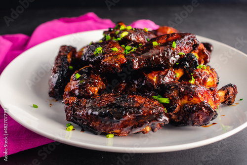 Chinese Five Spice Chicken Wings With Soy, Balsamic Reduction Glaze: Plate of sticky chicken wingettes and drumettes garnished with chives photo
