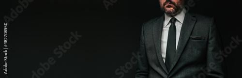 Panoramic low key portrait of handsome confident businessman in elegant grey suit