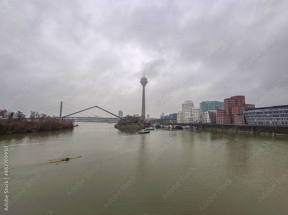 View of the Rhein river at a grey winter in Dusseldorf with the Rheinturm television tv tower and bridge,Germany, Europe.