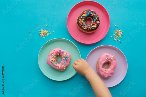Donuts on bright color plates and kids’ hand