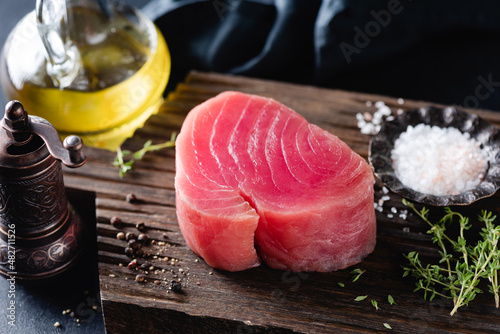 Raw pink tuna fillet and spices on a wooden background. Fish steak ready for cooking